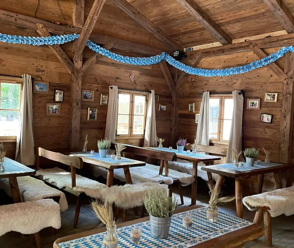 Gem&uuml;tliches Holzrestaurant mit blauen Dekorationen, Holztischen und -b&auml;nken sowie Pflanzen auf den Tischen.