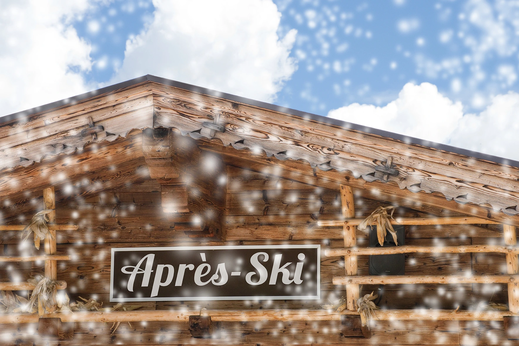 Holzhütte mit "Après-Ski"-Schild, umgeben von Schnee und einem blauen Himmel mit Wolken.
