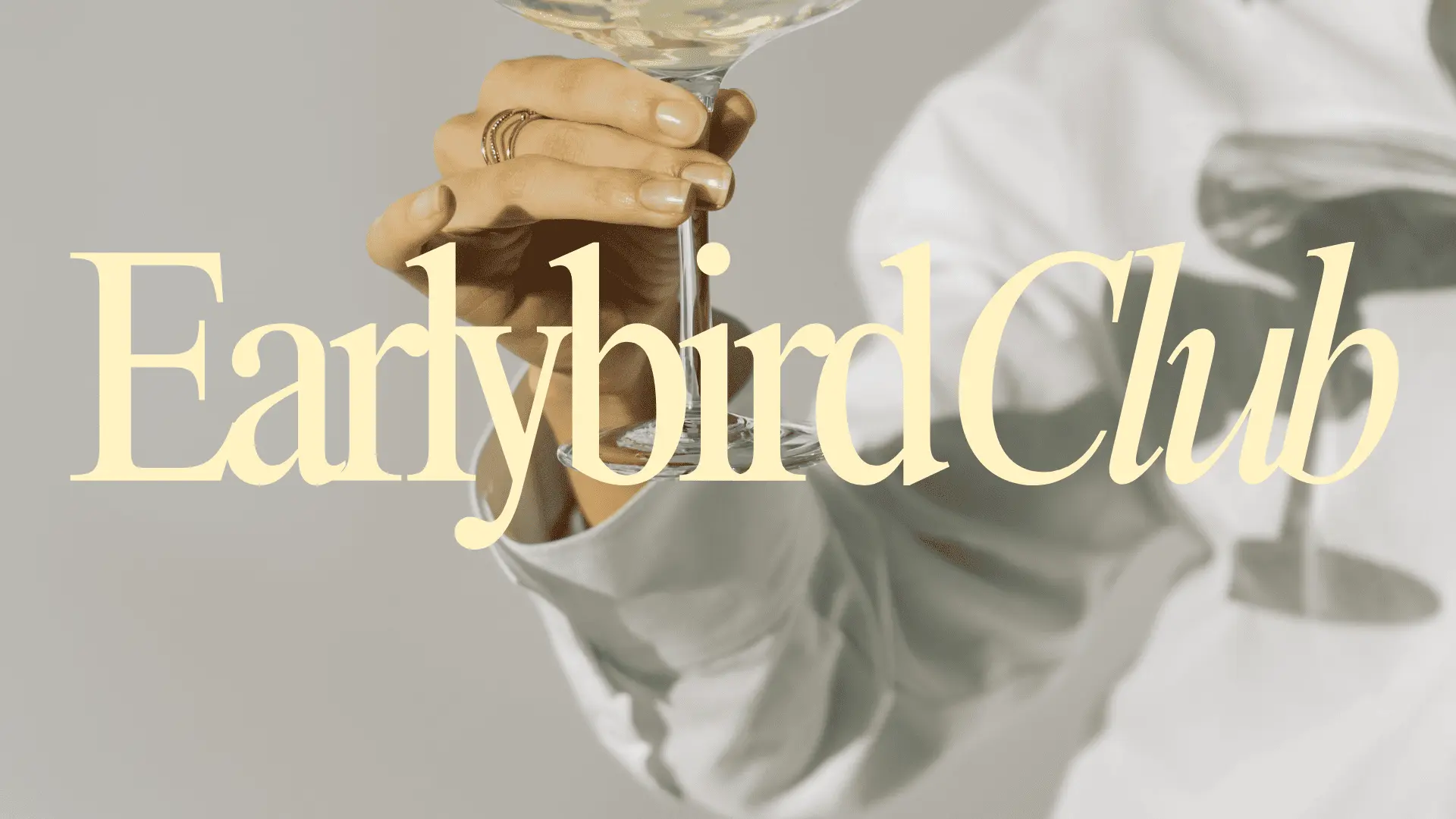Ein Hand hält ein Cocktailglas, daneben der Text "Earlybird Club" in eleganter Schrift.
