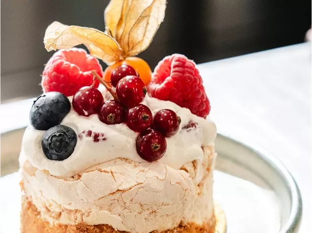 Eine Sahnetorte mit einer Dekoration aus Himbeeren, Heidelbeeren, roten Johannisbeeren und einer Physalis.