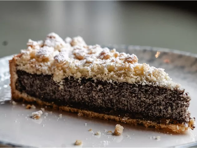 Ein St&uuml;ck Mohnkuchen mit streuseligem Belag auf einem wei&szlig;en Teller.