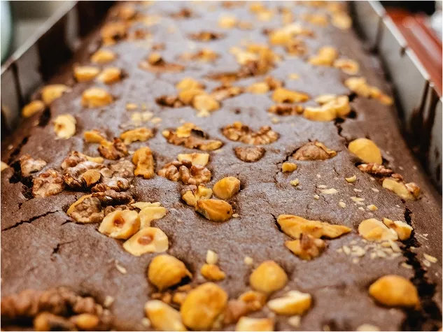 Schokoladenkuchen mit gehackten N&uuml;ssen und Haseln&uuml;ssen, gleichm&auml;&szlig;ig auf der Oberfl&auml;che verteilt.