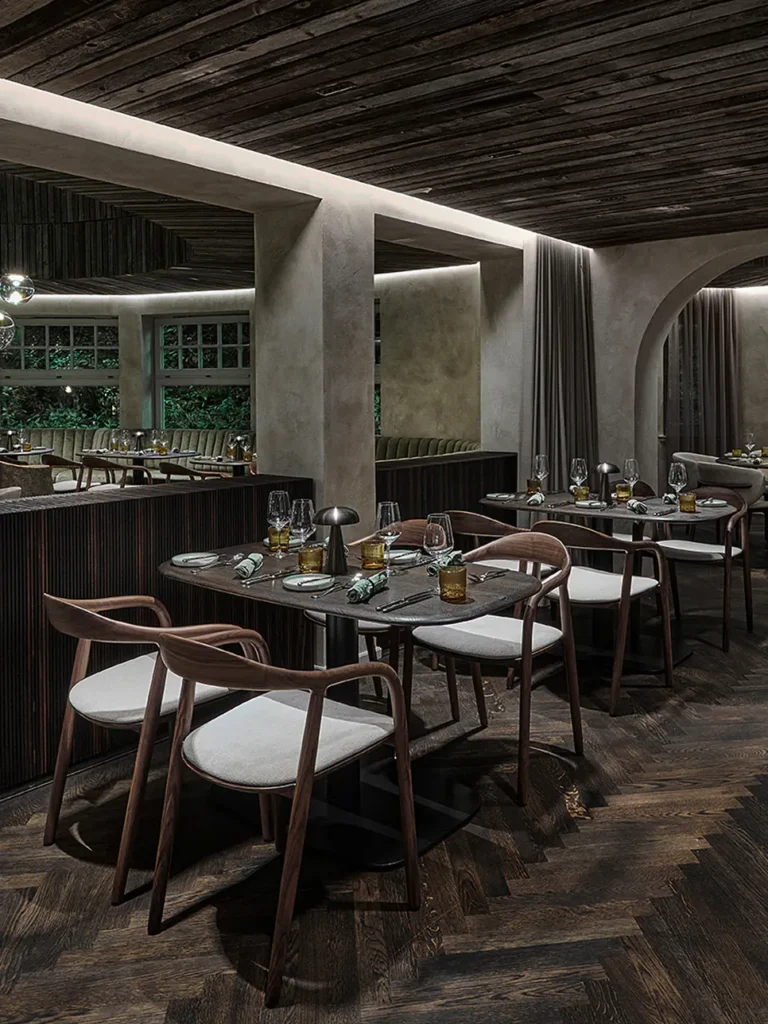 Elegantes Restaurantinterieur mit Holzböden, stilvollen Tischen und Stühlen sowie sanfter Beleuchtung.