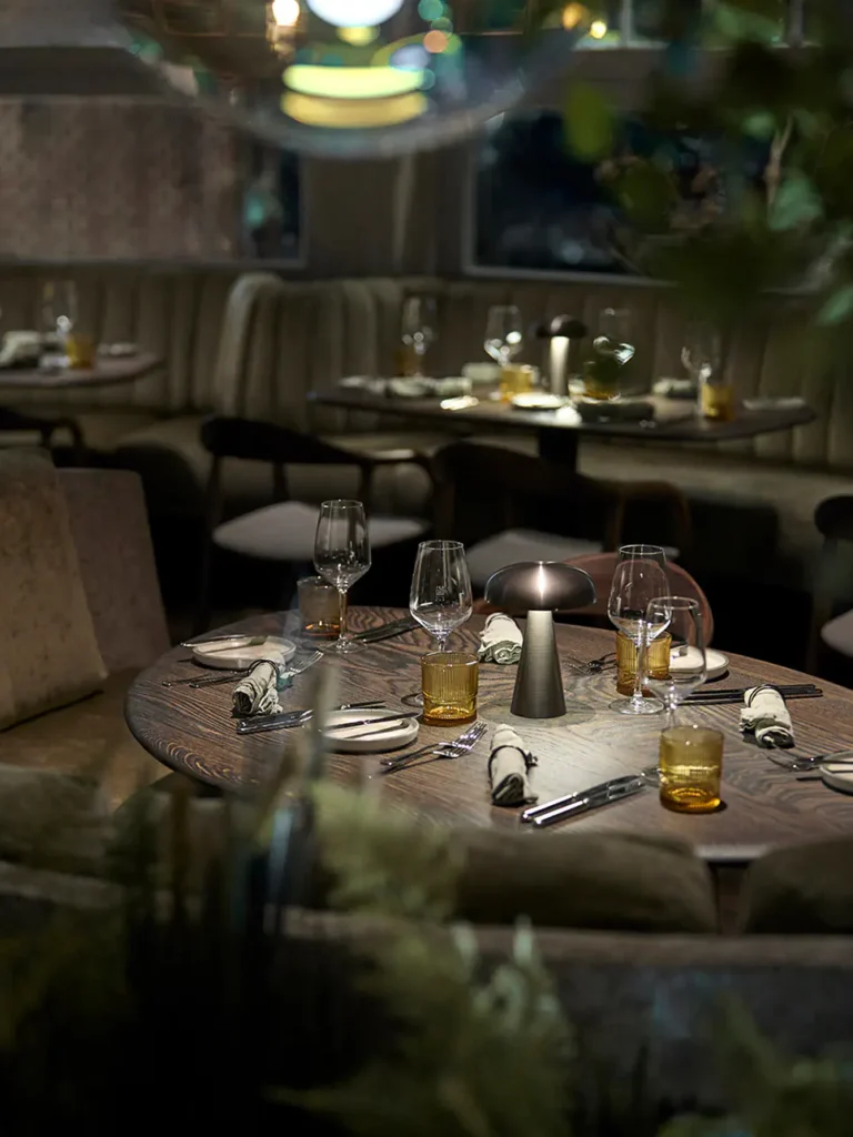 Elegante Restaurantatmosphäre mit gedeckten Tischen, Gläsern und warmem Licht.