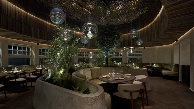 Elegantes Restaurant mit geschwungenen Sitzgelegenheiten, Pflanzen und stilvollen Beleuchtungskugeln an einer modernen Decke.