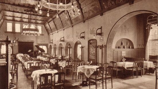 Historisches Restaurant mit Holztischen, St&uuml;hlen und dekorativen W&auml;nden in warmen Farbt&ouml;nen.